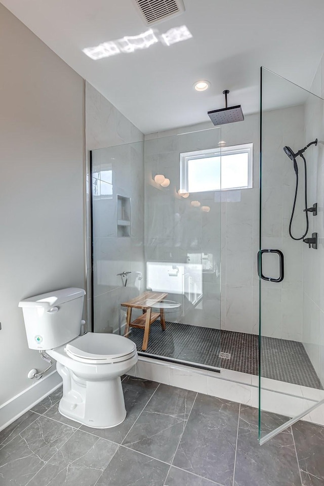 bathroom with a shower with shower door and toilet