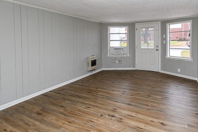 unfurnished room featuring wood-type flooring, heating unit, a wealth of natural light, and cooling unit