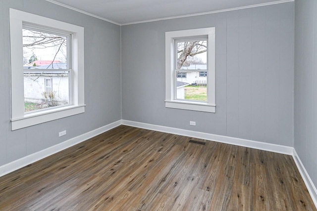 empty room featuring dark hardwood / wood-style floors, plenty of natural light, and ornamental molding