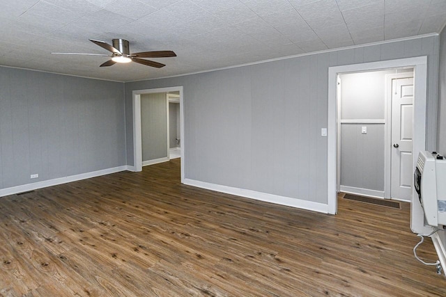 spare room featuring heating unit, ceiling fan, dark wood-type flooring, and ornamental molding