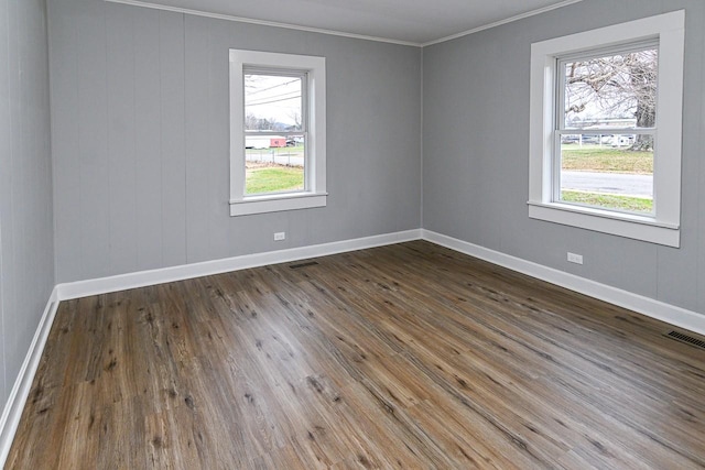 empty room featuring dark hardwood / wood-style flooring, plenty of natural light, and ornamental molding