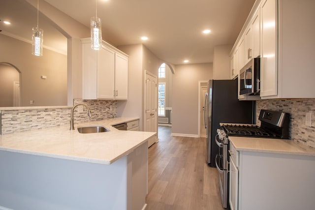 kitchen featuring kitchen peninsula, pendant lighting, white cabinetry, appliances with stainless steel finishes, and sink