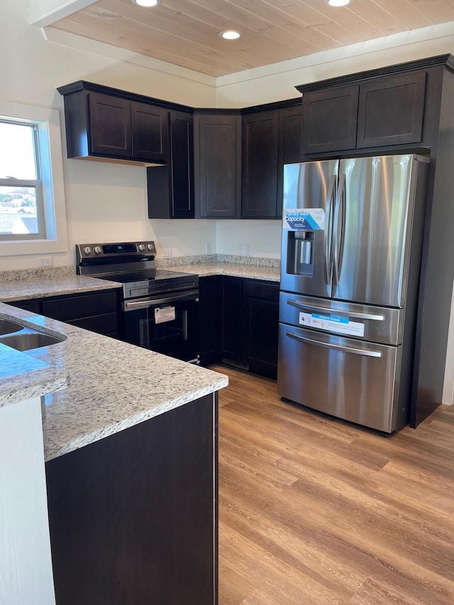 kitchen featuring electric stove, stainless steel fridge, light stone countertops, and light wood-type flooring