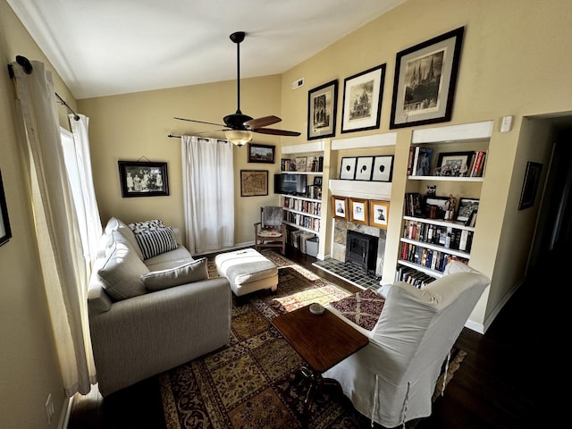 living room featuring dark hardwood / wood-style flooring, ceiling fan, vaulted ceiling, and a tiled fireplace