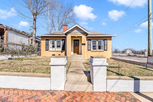 bungalow featuring a shingled roof, a front yard, fence, and a chimney