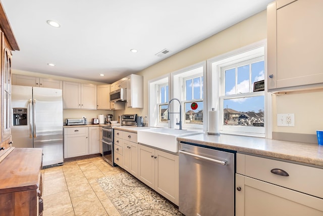 kitchen featuring visible vents, appliances with stainless steel finishes, light countertops, a sink, and recessed lighting