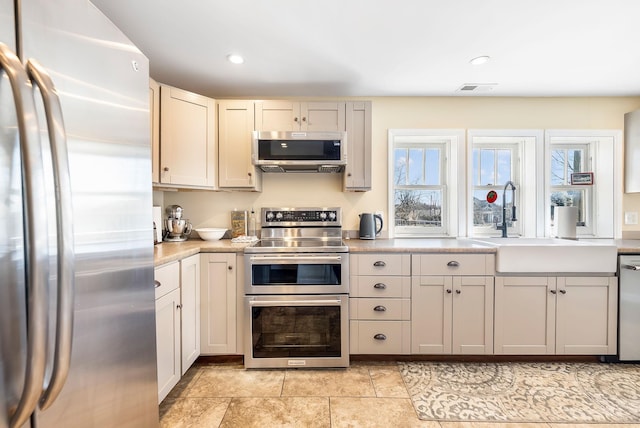 kitchen featuring visible vents, stainless steel appliances, a sink, and a wealth of natural light