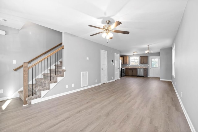 unfurnished living room featuring light wood-type flooring and ceiling fan with notable chandelier