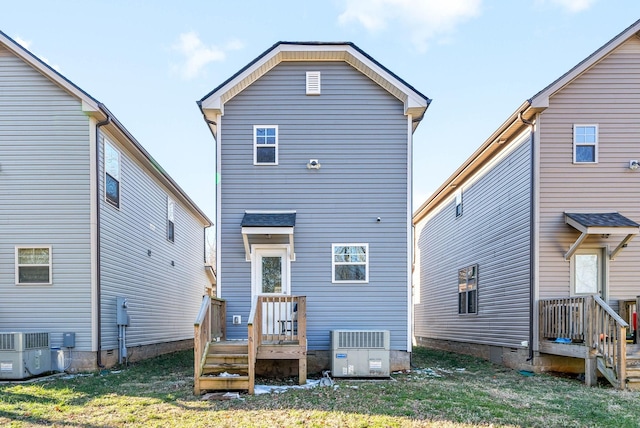 rear view of house with central air condition unit and a lawn