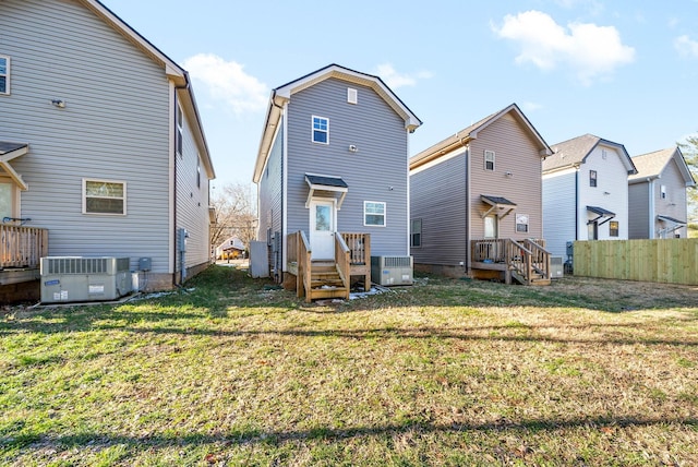 rear view of property featuring a lawn and central AC unit