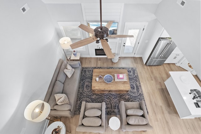 living room with a large fireplace, ceiling fan, and light wood-type flooring