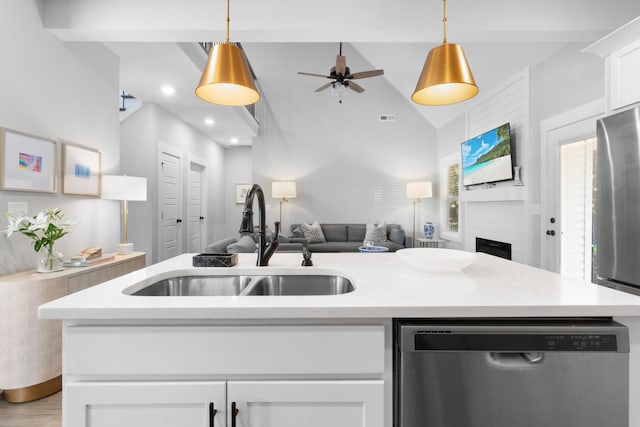 kitchen with vaulted ceiling, a kitchen island with sink, white cabinets, appliances with stainless steel finishes, and sink