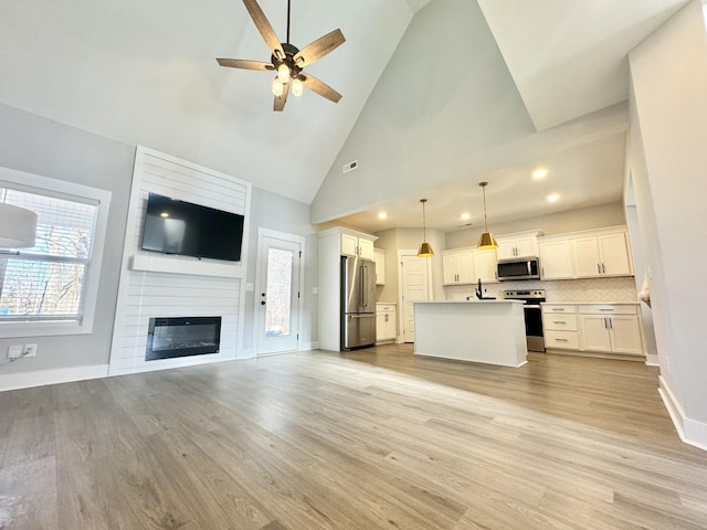 unfurnished living room featuring sink, light hardwood / wood-style flooring, high vaulted ceiling, and a fireplace