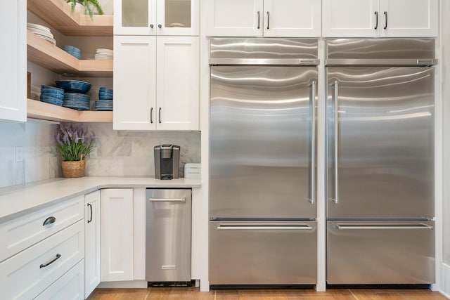 kitchen featuring built in refrigerator, decorative backsplash, and white cabinetry