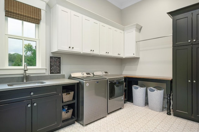 clothes washing area featuring washing machine and dryer, cabinets, and sink