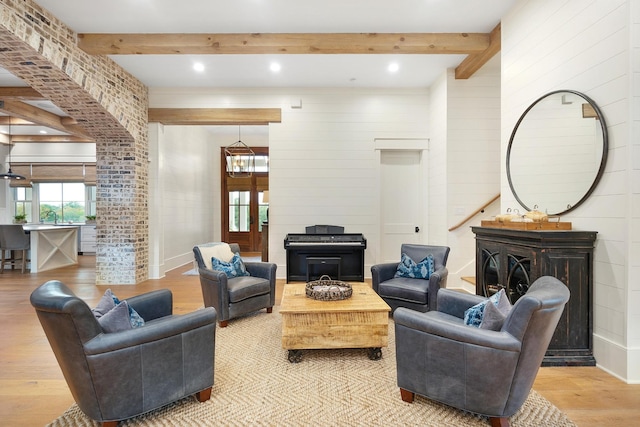 living room featuring sink, a notable chandelier, beamed ceiling, and light hardwood / wood-style flooring