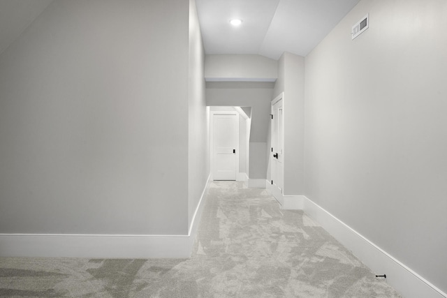 corridor with lofted ceiling and light colored carpet