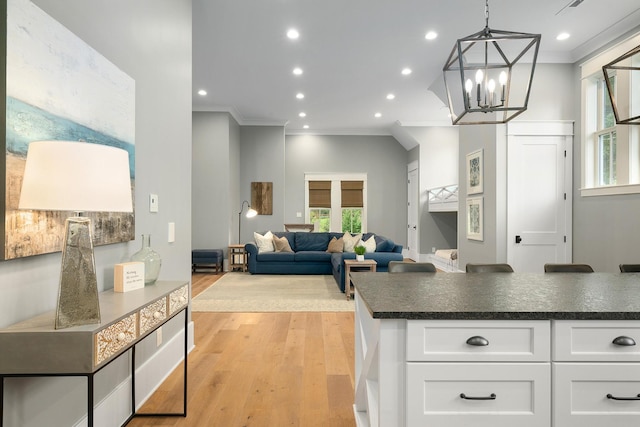 kitchen with white cabinets, hanging light fixtures, light hardwood / wood-style floors, and ornamental molding