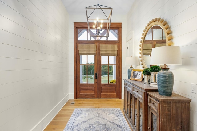 foyer featuring light hardwood / wood-style flooring, french doors, and an inviting chandelier