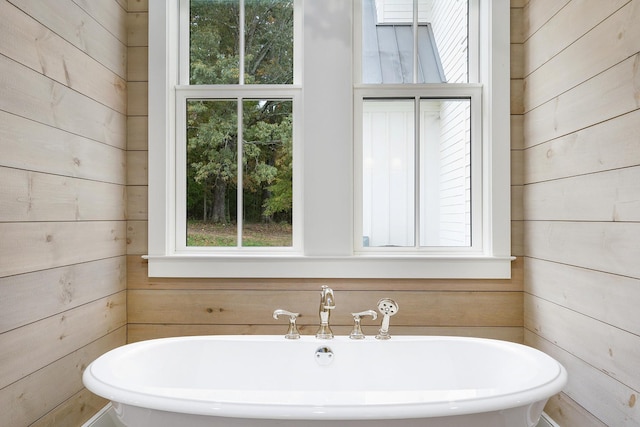 bathroom featuring a washtub and wooden walls