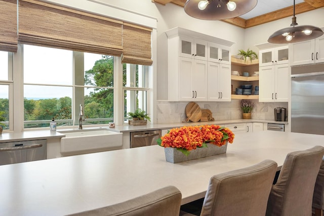 kitchen with pendant lighting, stainless steel appliances, tasteful backsplash, white cabinets, and sink