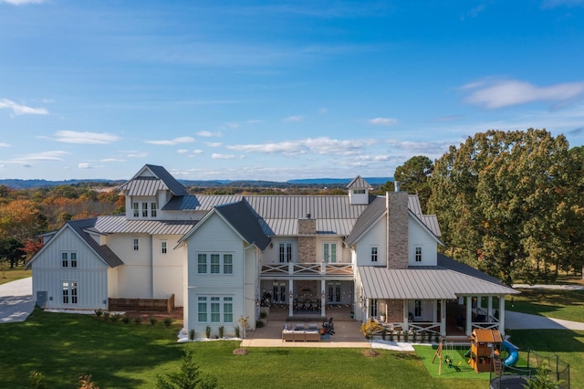 back of house featuring a yard, a playground, and a patio