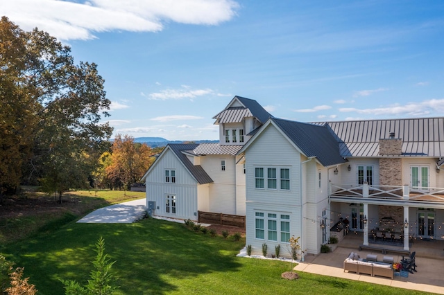 back of house with a patio area, outdoor lounge area, french doors, a balcony, and a lawn