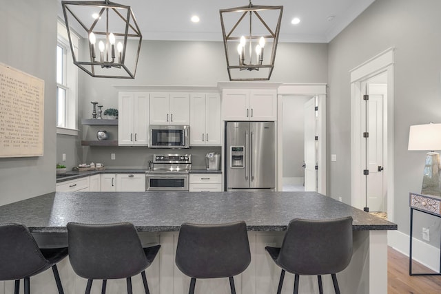 kitchen with white cabinets, appliances with stainless steel finishes, pendant lighting, and a kitchen breakfast bar