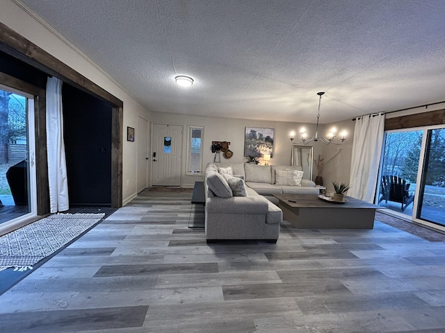 unfurnished living room with an inviting chandelier, a textured ceiling, and hardwood / wood-style floors