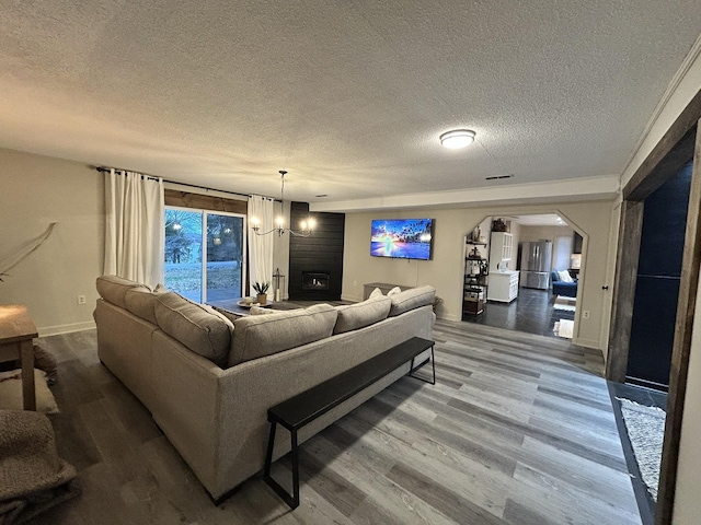 living room featuring a textured ceiling, a fireplace, hardwood / wood-style flooring, and a notable chandelier