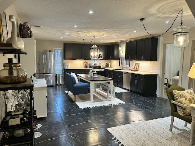 kitchen featuring sink, stainless steel appliances, a textured ceiling, and hanging light fixtures