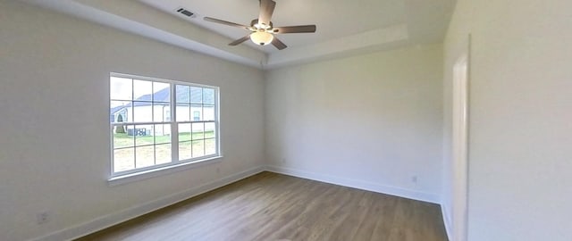 spare room featuring ceiling fan, a raised ceiling, and wood-type flooring