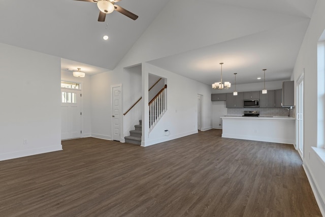 unfurnished living room featuring high vaulted ceiling, sink, dark hardwood / wood-style flooring, and ceiling fan with notable chandelier