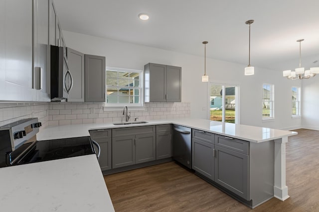 kitchen with kitchen peninsula, appliances with stainless steel finishes, gray cabinetry, decorative light fixtures, and sink