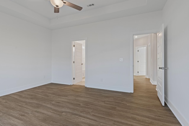 spare room featuring ceiling fan, dark hardwood / wood-style flooring, and a raised ceiling