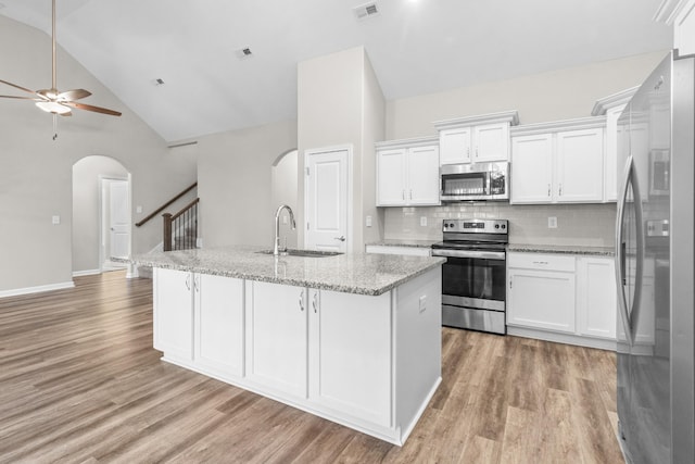 kitchen with sink, stainless steel appliances, white cabinetry, and a center island with sink