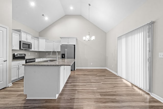 kitchen featuring an island with sink, white cabinetry, appliances with stainless steel finishes, dark stone countertops, and sink