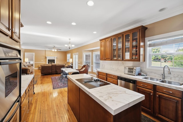 kitchen featuring appliances with stainless steel finishes, plenty of natural light, a kitchen island, sink, and ceiling fan with notable chandelier