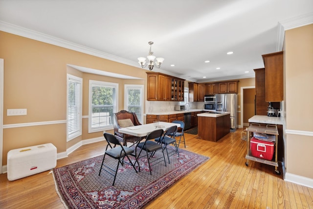 dining area featuring sink, ornamental molding, and light hardwood / wood-style floors