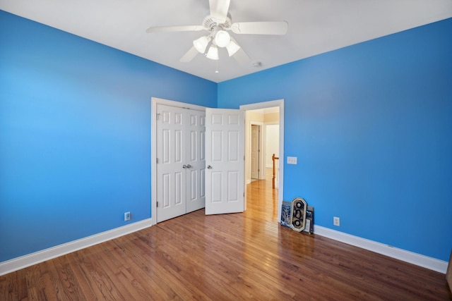 unfurnished bedroom featuring ceiling fan, a closet, and hardwood / wood-style flooring