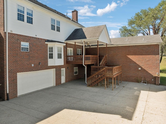 rear view of property with a deck and a garage