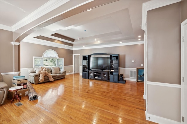 living room with crown molding, hardwood / wood-style floors, decorative columns, and a tray ceiling