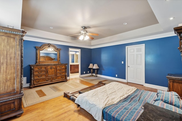 bedroom with ceiling fan, ensuite bath, light hardwood / wood-style floors, and a raised ceiling