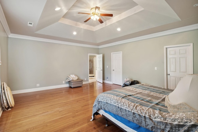 bedroom featuring ornamental molding, ceiling fan, a tray ceiling, and hardwood / wood-style flooring