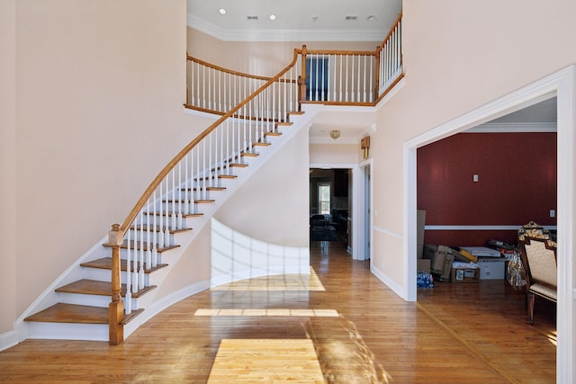 stairs featuring a towering ceiling, crown molding, and hardwood / wood-style flooring