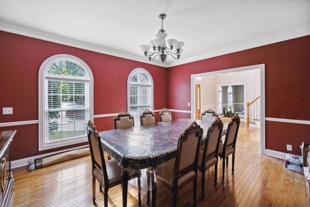 dining space featuring an inviting chandelier, ornamental molding, and light hardwood / wood-style flooring