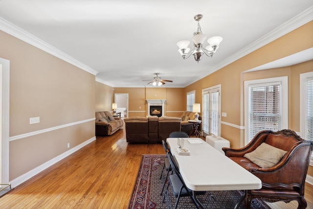 dining area with ornamental molding, ceiling fan with notable chandelier, and wood-type flooring