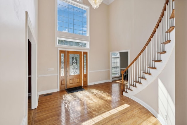 entryway featuring a notable chandelier, light wood-type flooring, and a towering ceiling