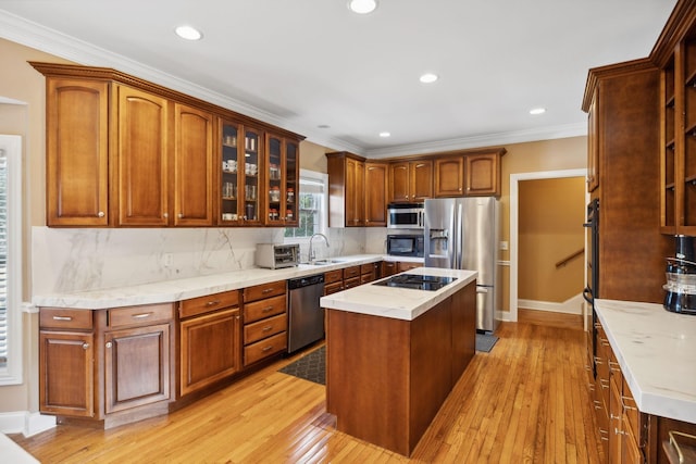 kitchen with sink, a center island, light hardwood / wood-style floors, backsplash, and appliances with stainless steel finishes