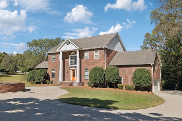 greek revival house with a front yard and a garage